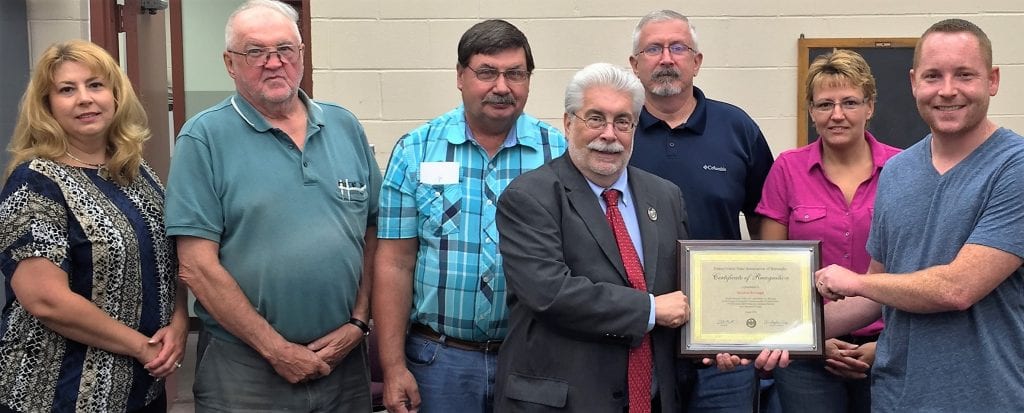 Foreground, Left to Right: Ed Knittel, Senior Director, Education and Sustainability, PSAB, presents a 125th anniversary commemorative plaque to Gordon Borough council president Michael Rader at their council meeting Tuesday, August 9, 2016. Background, Left to Right: Gordon Borough council vice-president Valerie Stitzer Dornsife, borough manager Paul Snyder, councilman Richard Babb, mayor George Brocious, councilperson Shannon Dumboski. Missing from photo: Councilmen Brian Hansbury, Jason Quick and Jeffrey Hoffman.